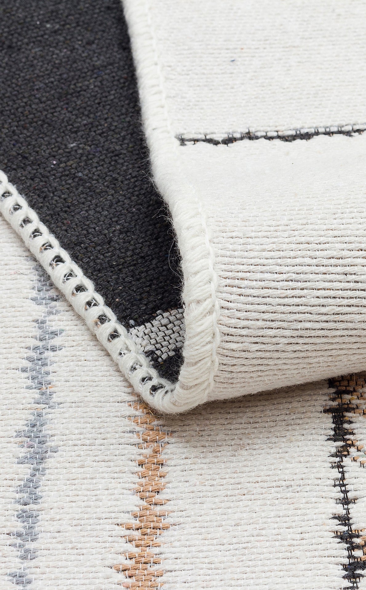 A close-up of the Fog Detail - Washable Double-Sided Kilims - AR40 shows cream fabric with stitched edges, subtle blue, brown, and grey lines. The reversible rug’s underside is dark grey.