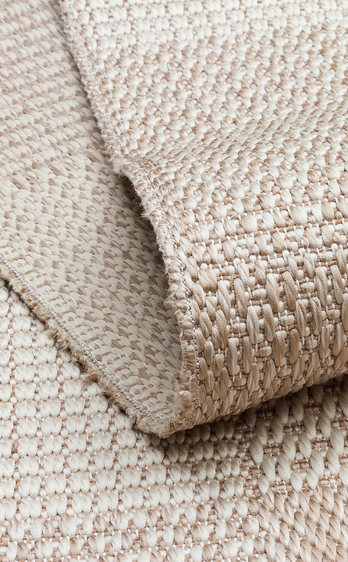 Close-up of the Natural Stitch - Kilim - MNO01 rug in beige and cream, showing its textured weave, folded corner, and detailed pattern.