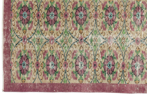 Load image 1 in gallery view. Distressed beige rug with a repeating floral medallion pattern in magenta, green, and teal, featuring a wide solid border.