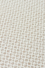 Close-up of the Earth Note - Kilim - MNO04 rug, showcasing its textured, off-white woven fabric with a repeating pattern of thick, tightly interlaced yarns for a timeless design.
