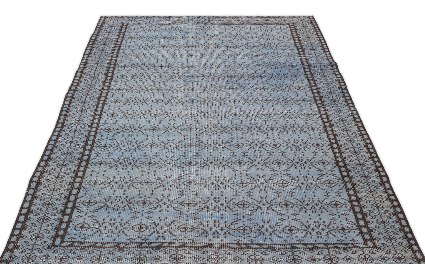 Light blue and dark brown distressed rug with a repeating geometric medallion pattern and a wide decorative border.