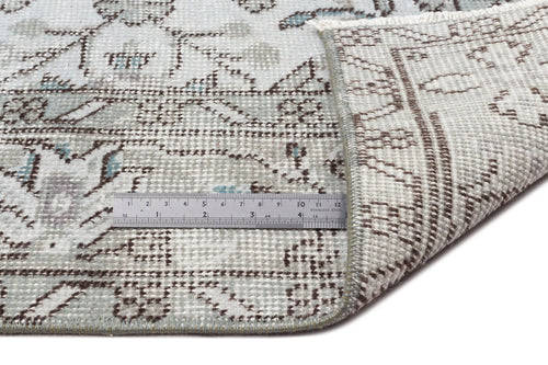 Load image 1 in gallery view. Light blue and brown distressed floral rug with a folded corner and a metal ruler for scale on a white background.