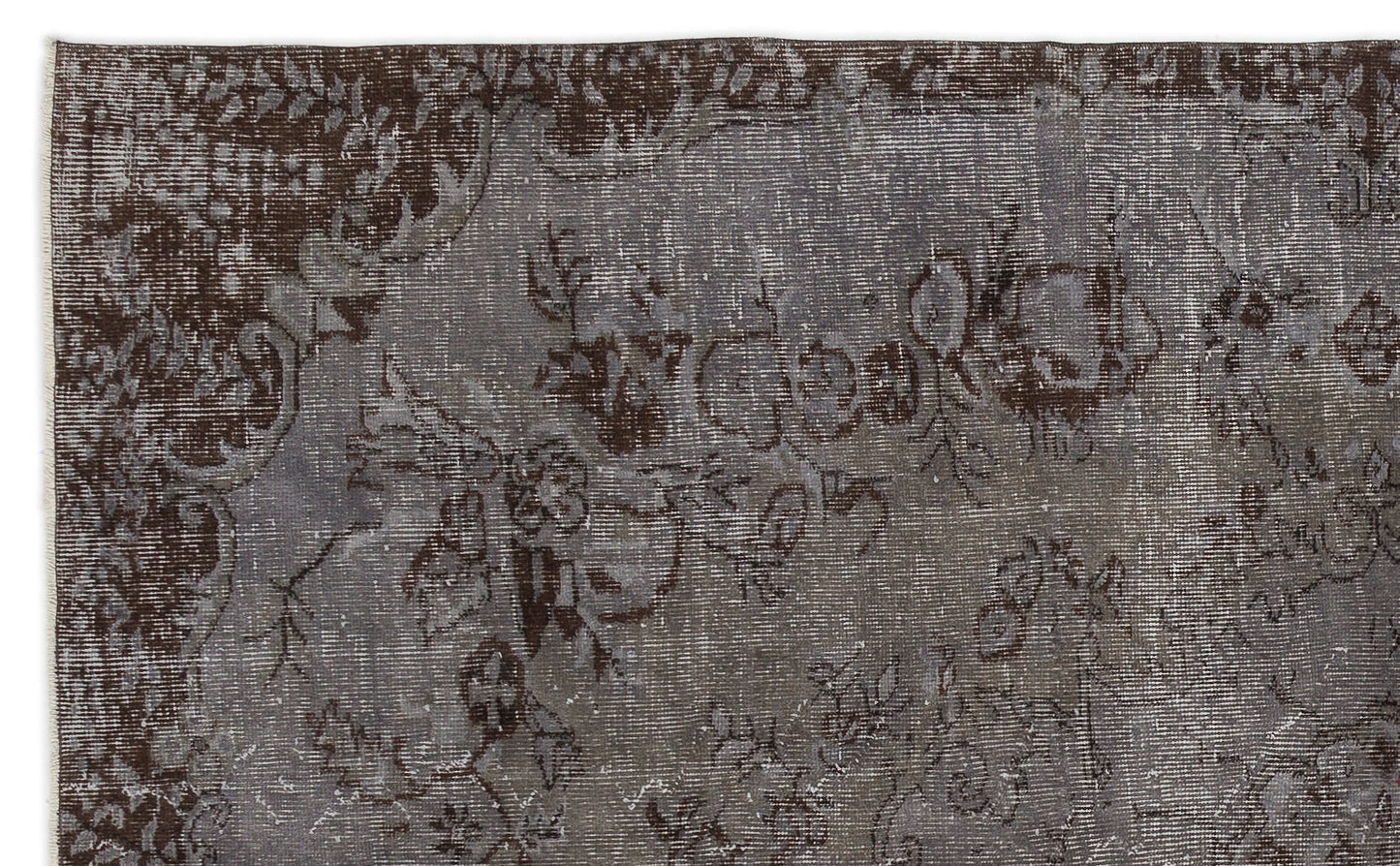 Dark brown and grey distressed rug with a faded traditional floral pattern.