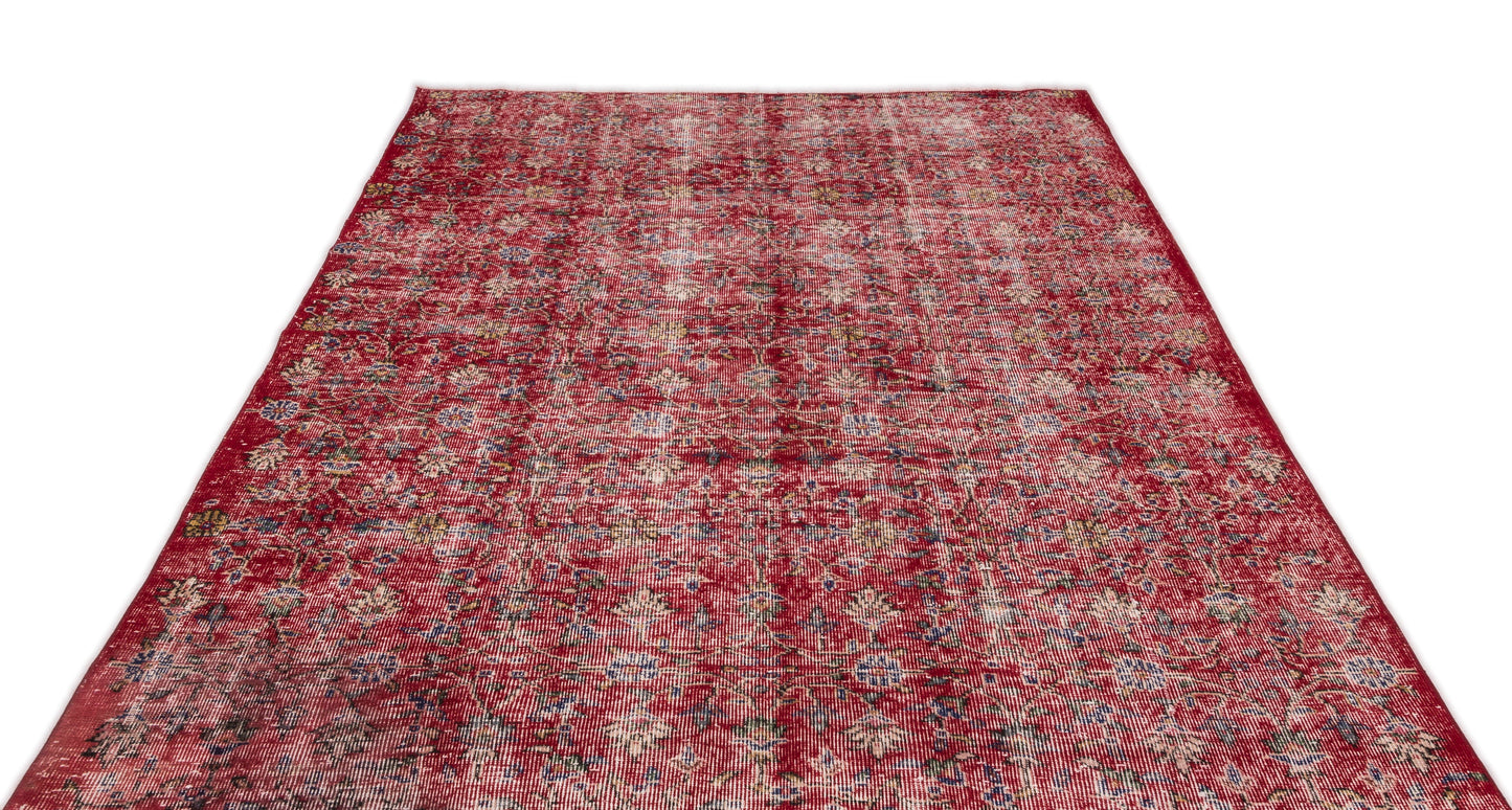 Distressed red rug with a faded floral medallion pattern and hints of blue and yellow on a white background.
