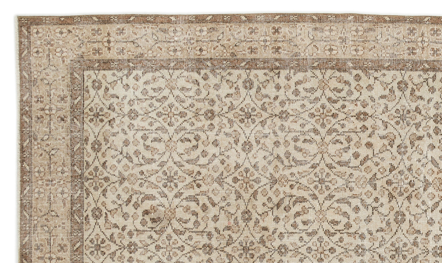 A close-up of the Pavia - Vintage Floral Rug (5'7 x 9'5), a beige and light brown Anatolian hand-woven piece with an intricate symmetrical floral and vine design, subtle distressed texture, and decorative border.