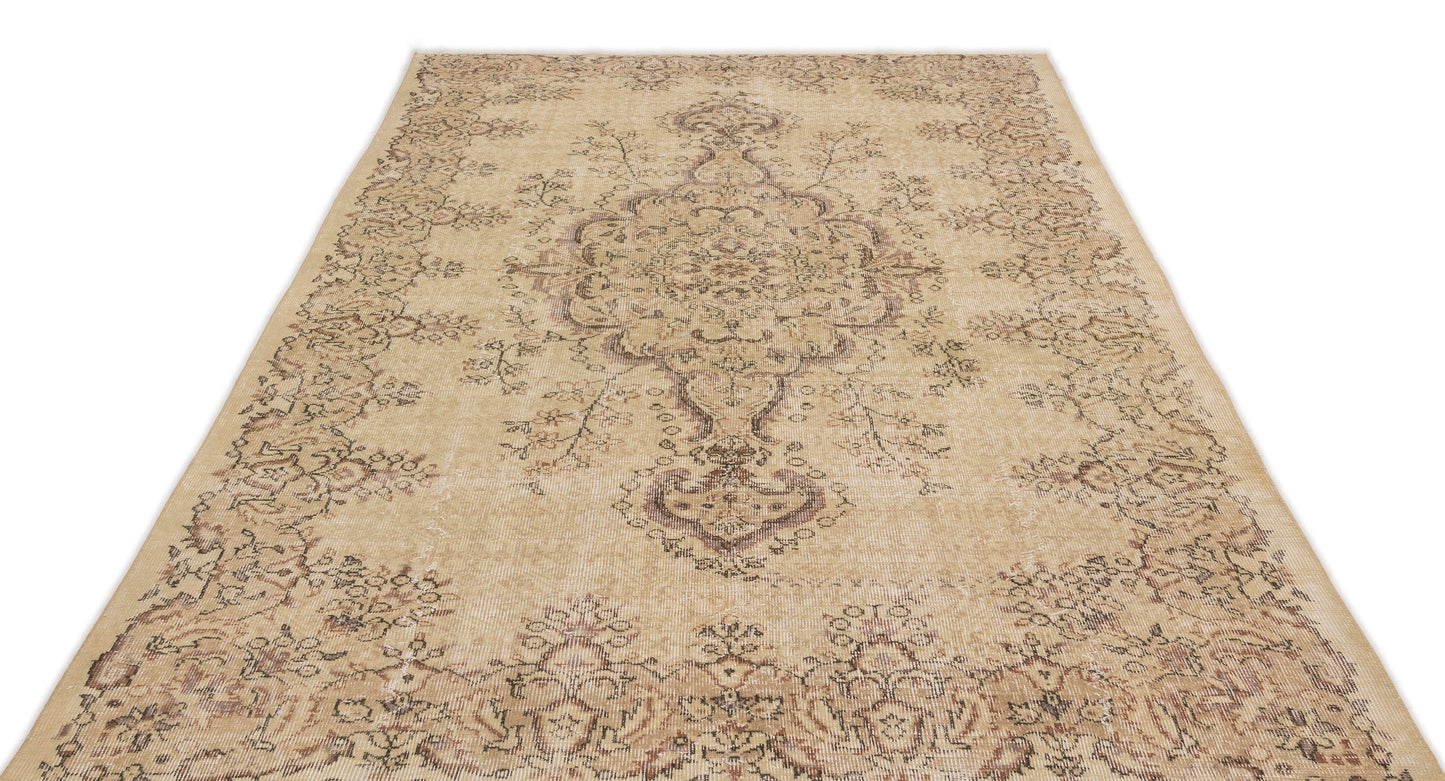 Beige and brown distressed area rug with a traditional central medallion and floral border pattern.