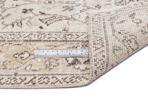 Load image 1 in gallery view. Beige and brown distressed traditional rug with a folded corner and a metal ruler for scale on a white background.