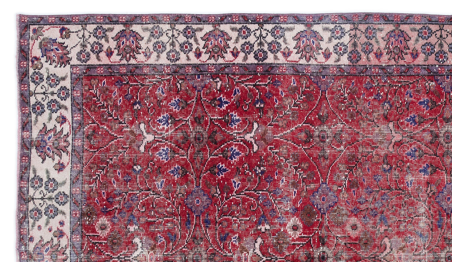Distressed red rug with a central floral medallion pattern and a cream border featuring intricate botanical motifs.