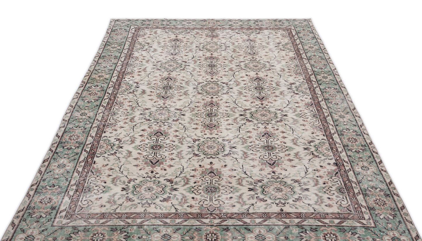 Cream, sage green, and mauve traditional rug with a distressed floral medallion pattern on a white background.