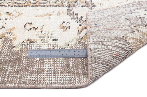 Load image 1 in gallery view. Beige and cream distressed rug with a faded traditional pattern, shown with a metal ruler for scale.