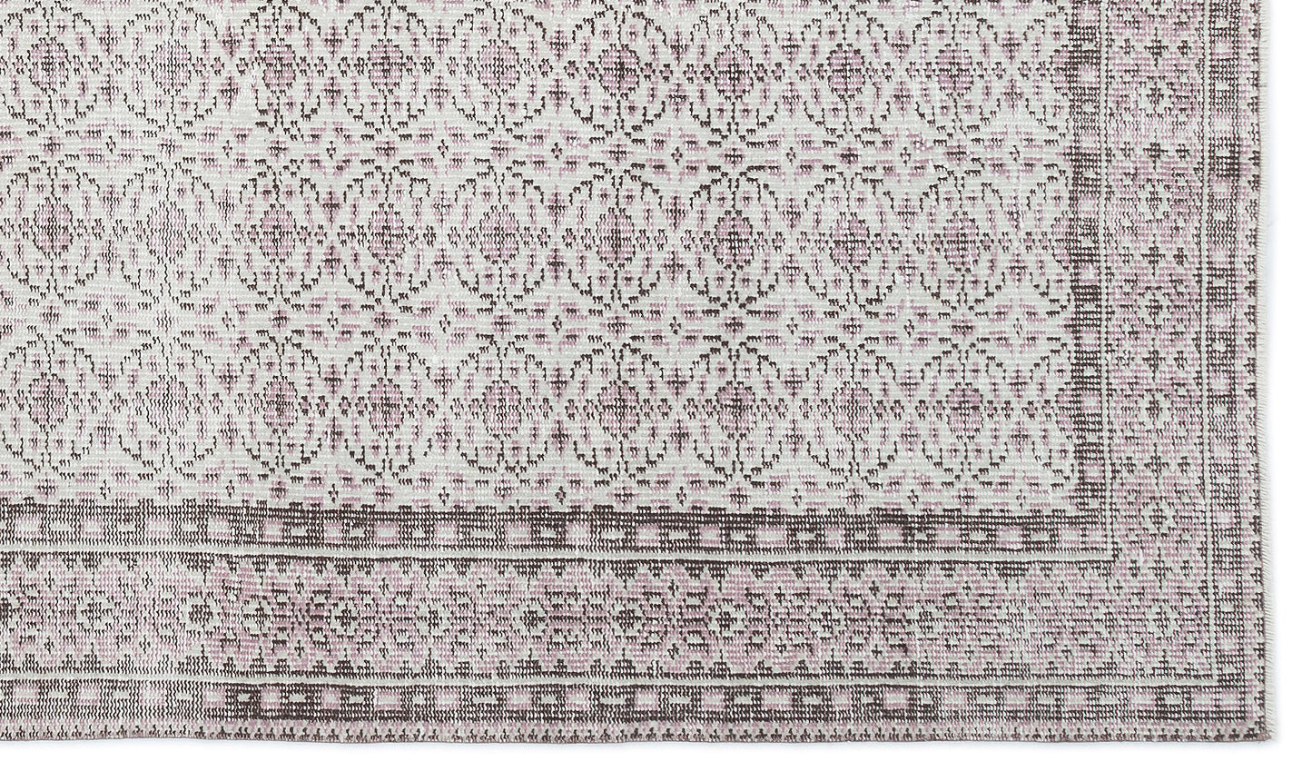 Off-white and dusty rose rug with a repeating geometric medallion pattern and a wide, detailed border.