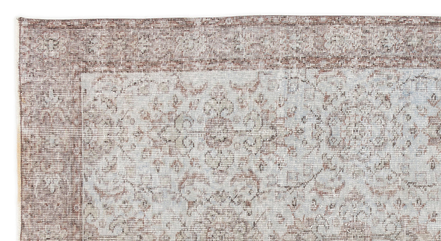 Distressed brown and light blue rug with a traditional floral medallion border and central pattern.
