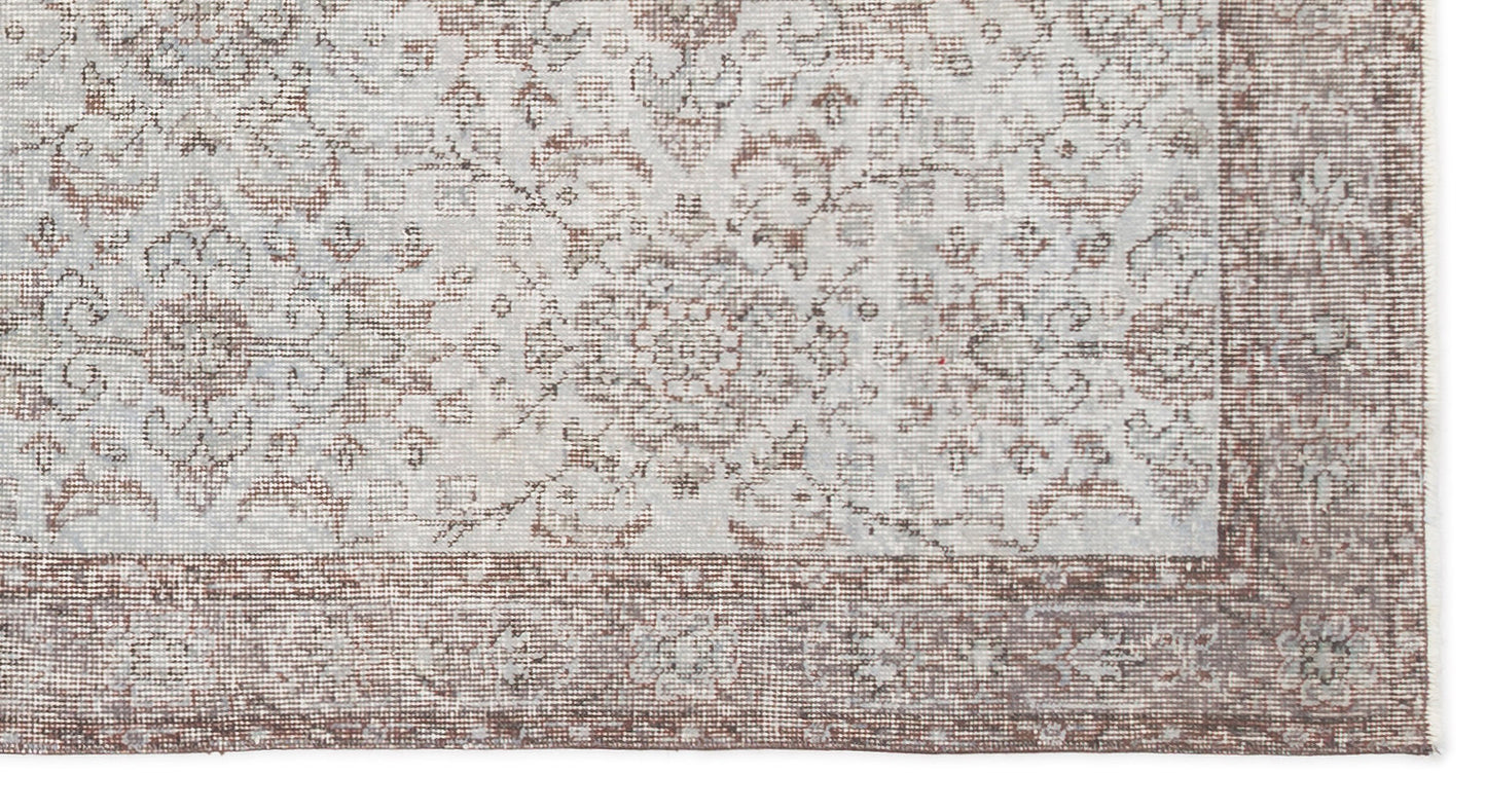Light gray and brown rug with a distressed traditional floral medallion pattern and a wide decorative border.