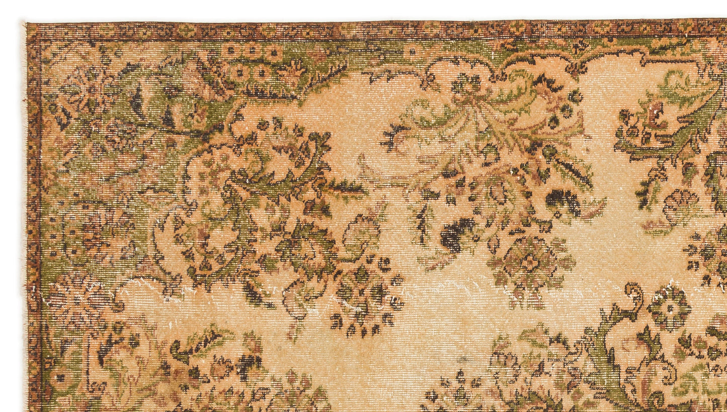 Distressed beige rug with a dark green and brown floral pattern and a decorative border.