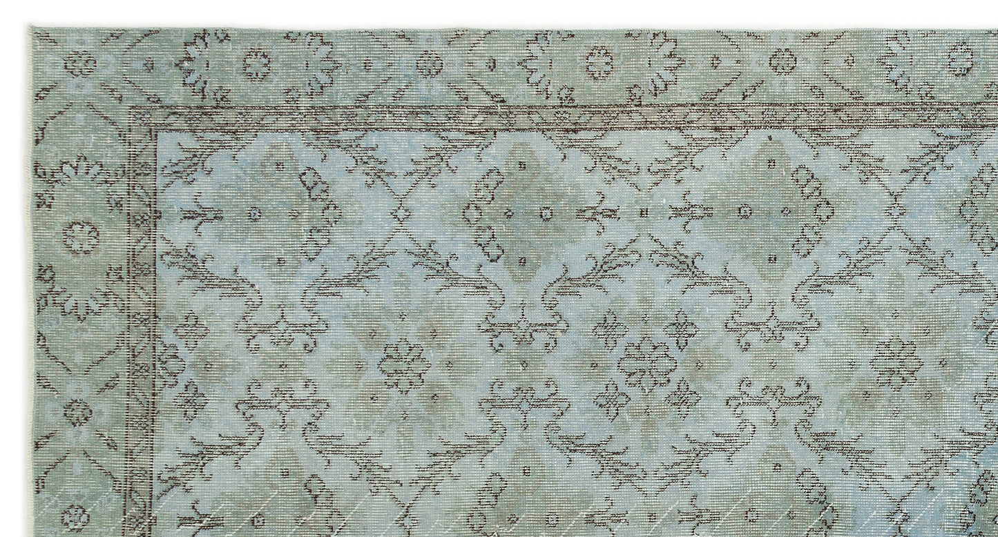 Light blue and sage green rug with a distressed traditional floral medallion pattern and a dark brown border.