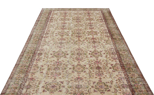 Load image 1 in gallery view. Beige vintage-style rug with a distressed floral medallion pattern in muted pink and green, isolated on white.