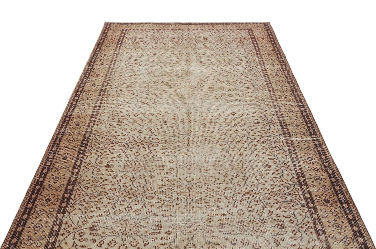Beige and brown vintage-style rug with a distressed floral pattern and a geometric border on a white background.