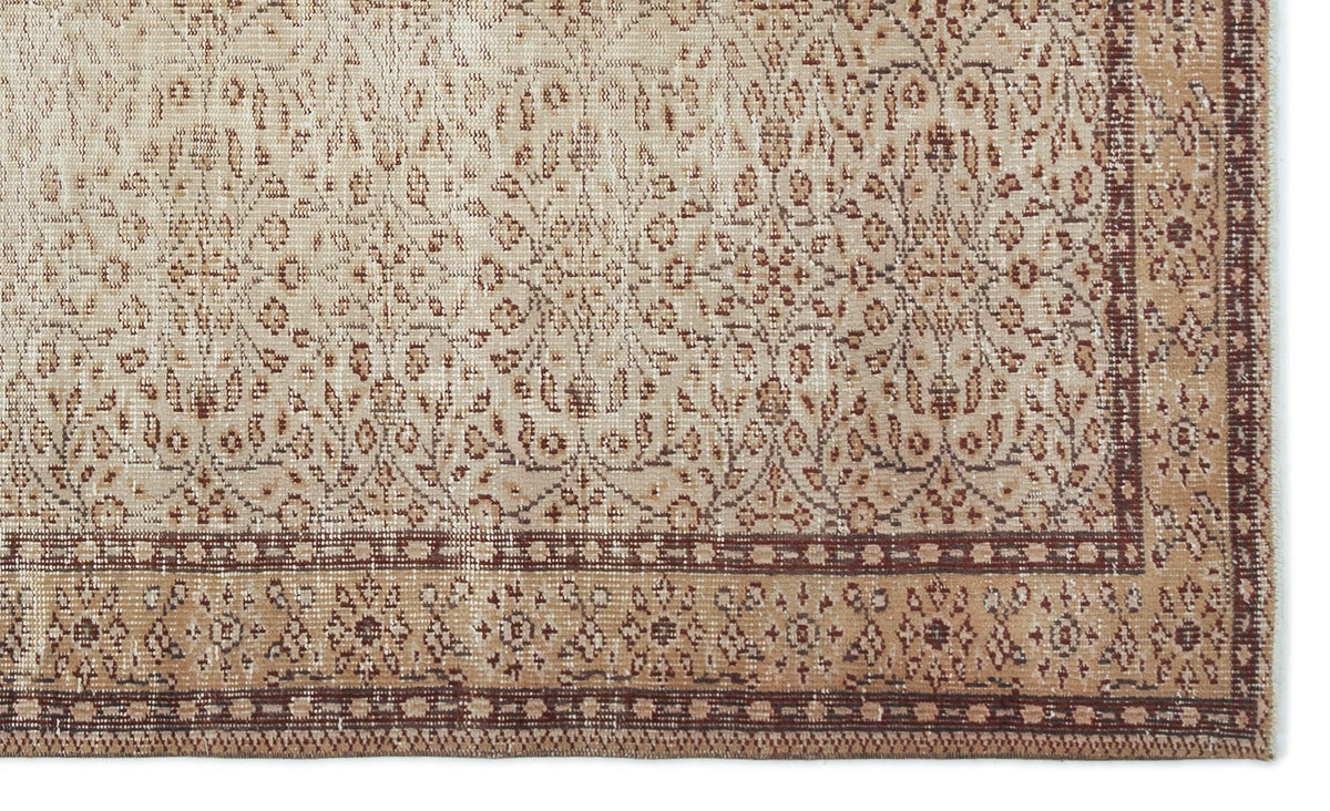 Beige and brown vintage-style rug with a distressed floral medallion pattern and a geometric border.