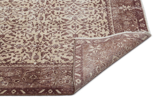Load image 1 in gallery view. Brown and beige rug with a traditional floral medallion pattern and a folded corner showing the woven backing.
