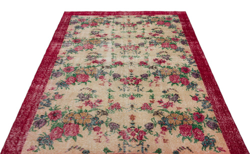 Load image 1 in gallery view. Beige vintage-style rug with a distressed floral pattern in red, green, and purple, featuring a wide red border.