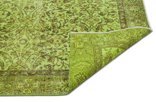 Load image 1 in gallery view. Lime green and brown distressed rug with a traditional floral medallion pattern and a folded corner.