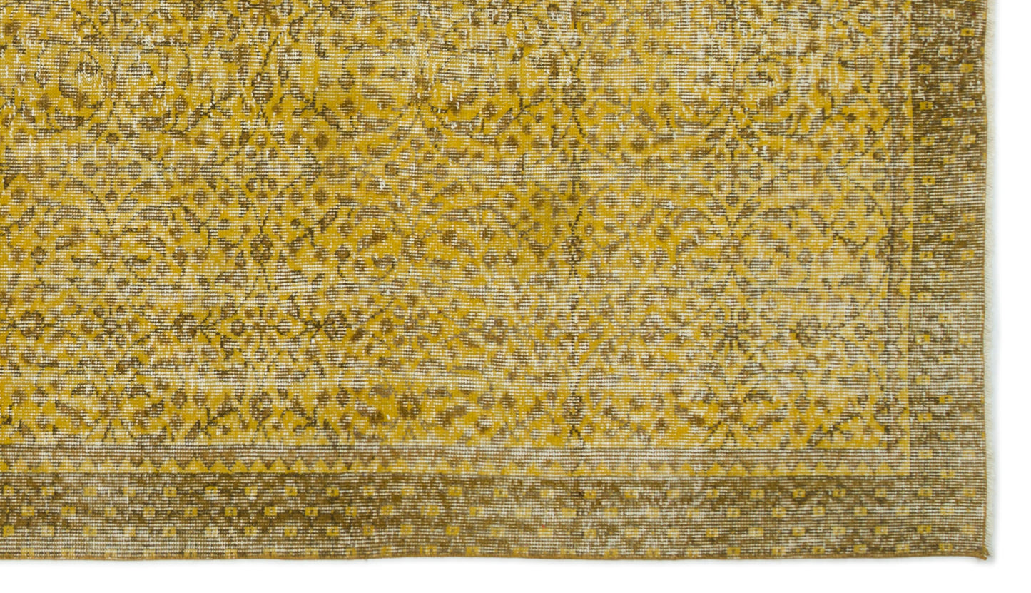 Mustard yellow and brown distressed rug with a traditional floral medallion pattern and a geometric border.