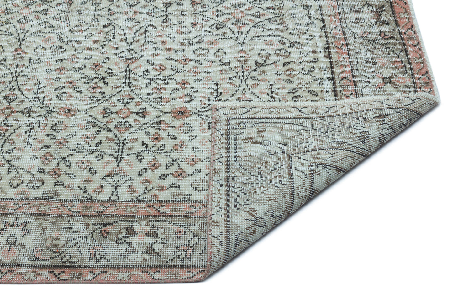 Beige and cream traditional rug with a distressed floral pattern and a folded corner, isolated on a white background.
