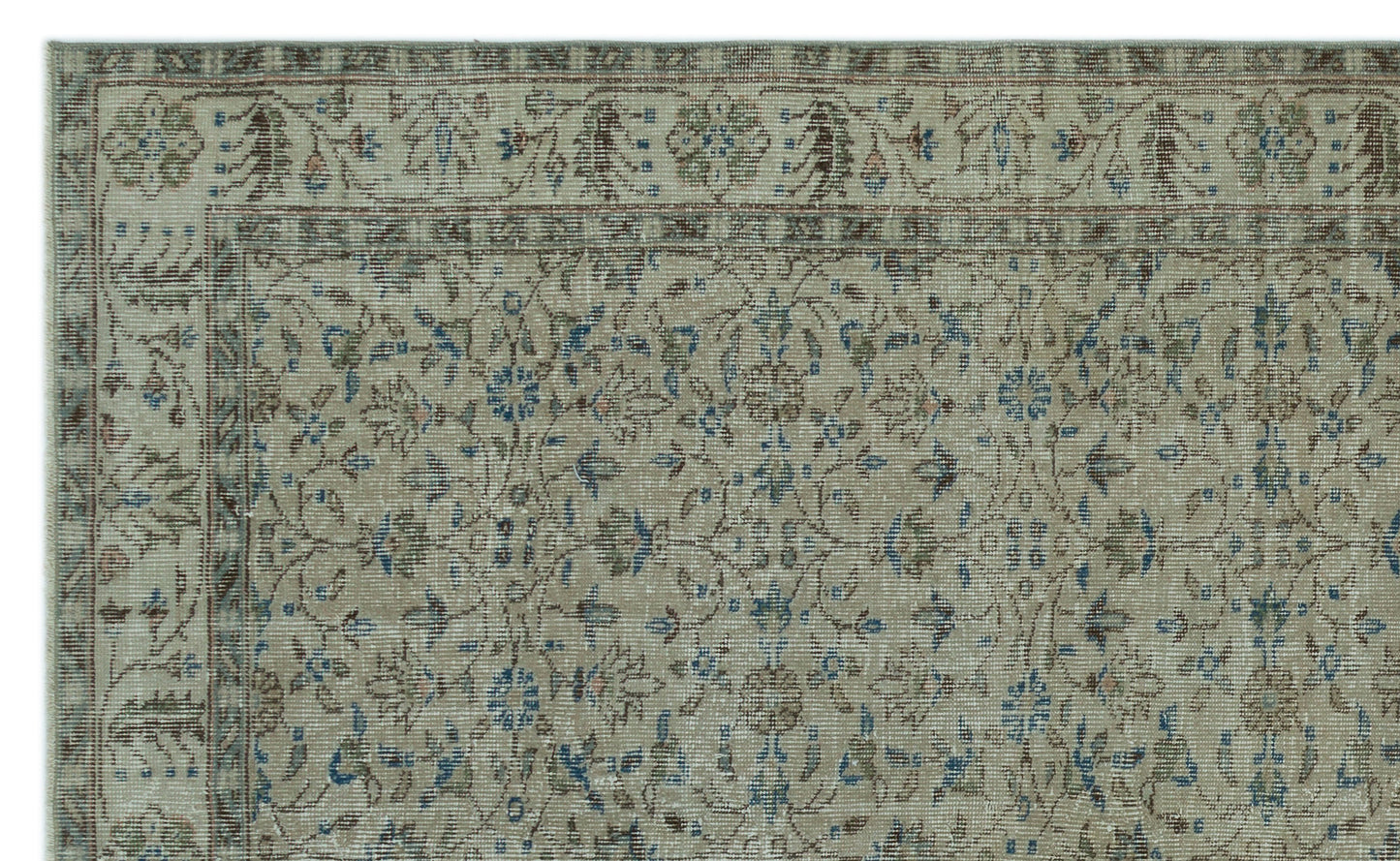 Beige traditional rug with a distressed floral medallion pattern in muted blue, brown, and sage green.