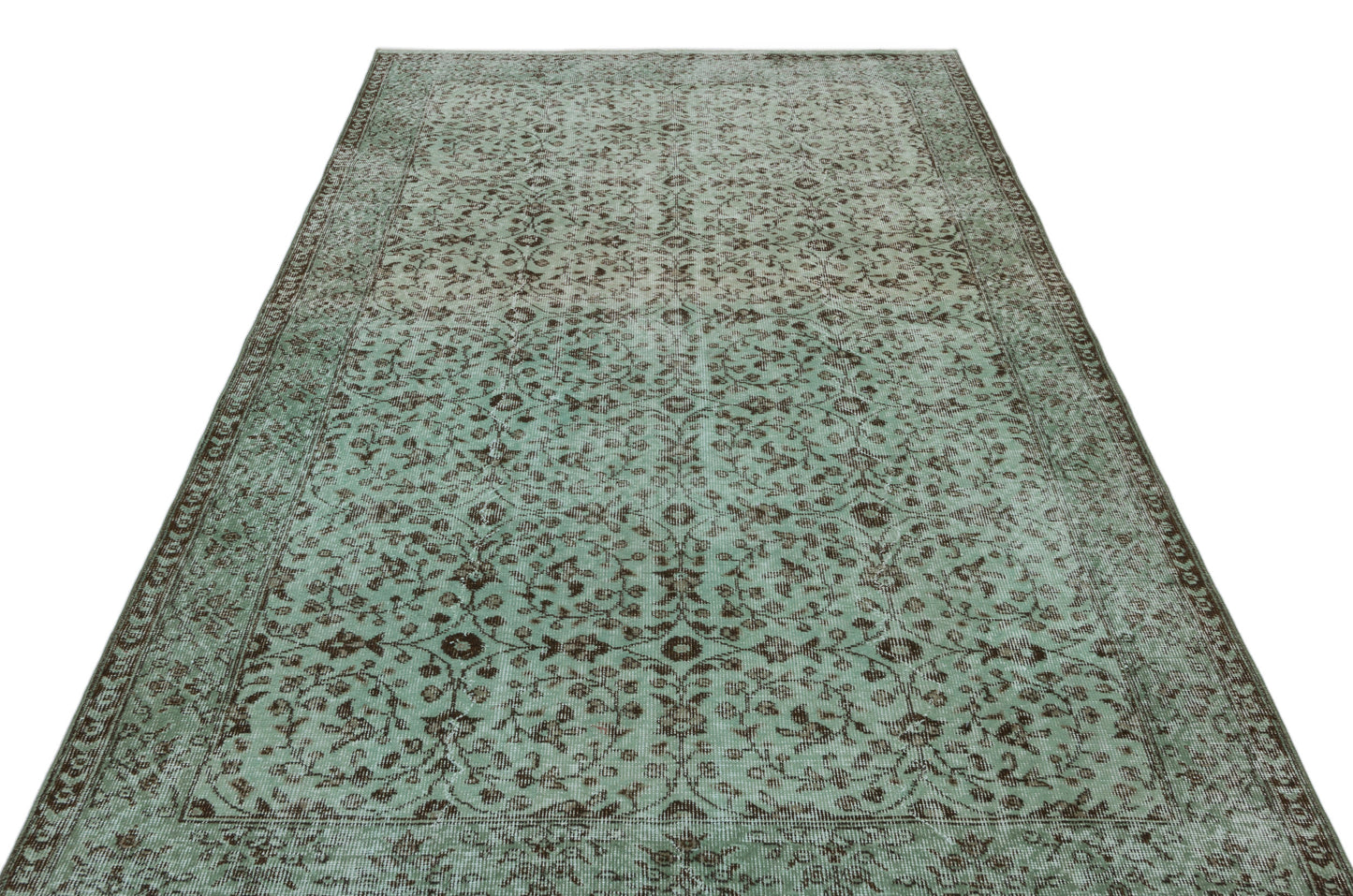 Sage green and brown vintage-style rug with a distressed floral vine pattern and a decorative border.