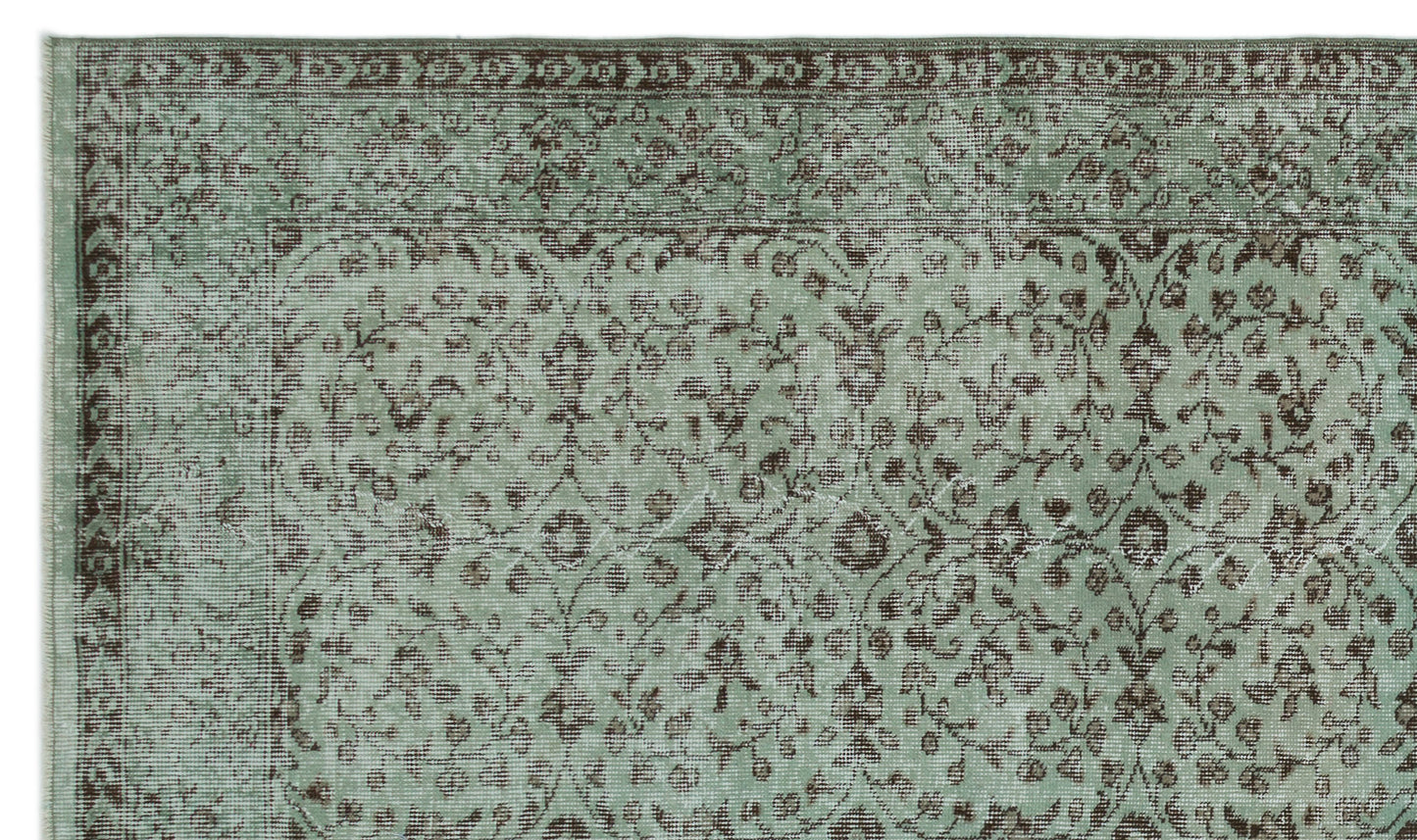 Sage green and brown distressed rug with a traditional floral vine pattern and a decorative border.