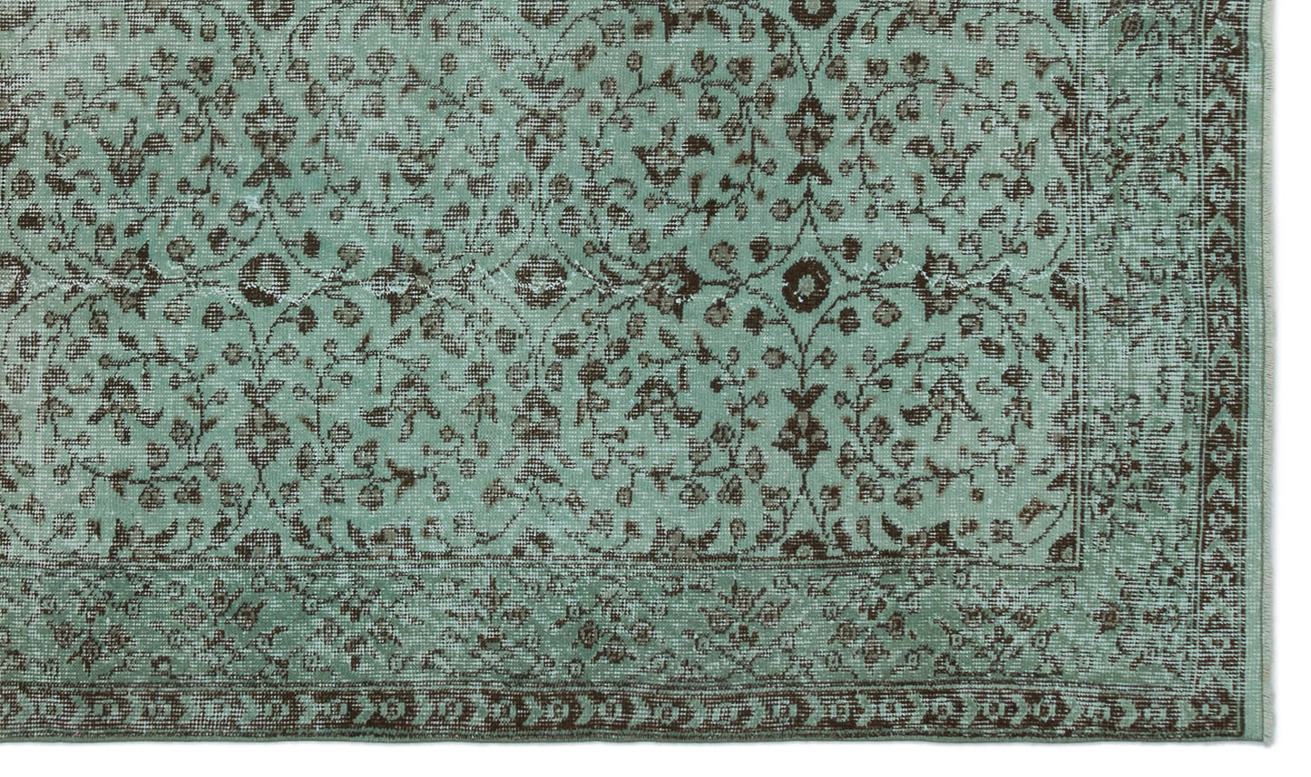 Distressed mint green rug with a dark brown floral vine pattern and a decorative border.