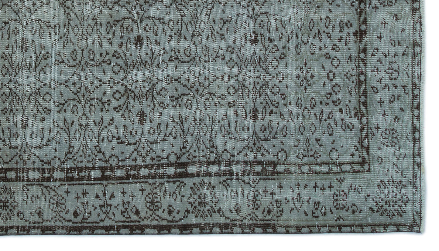 Distressed sage green and dark brown rug with a traditional floral medallion pattern and a decorative border.