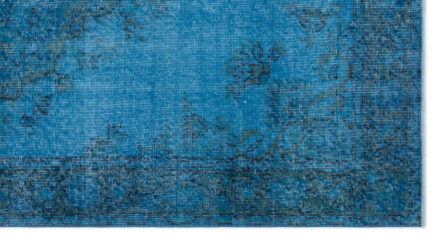 Bright blue rug with a distressed, faded floral medallion pattern and a dark border.