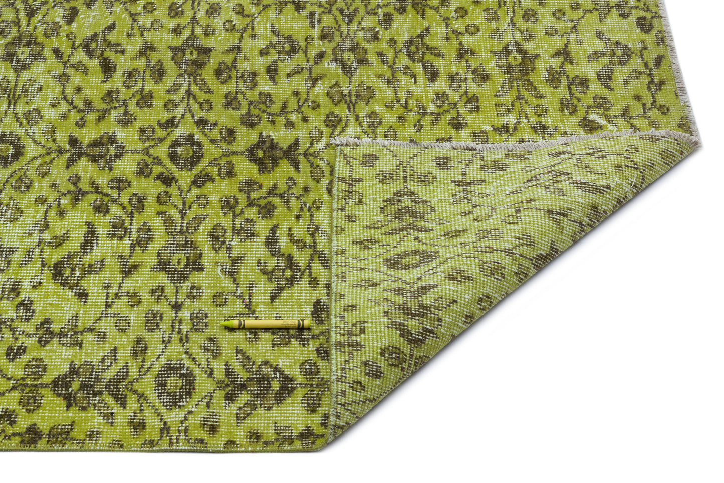 Chartreuse and dark brown floral patterned rug with a folded corner, isolated on a white background.