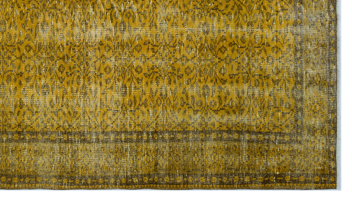 Mustard yellow and brown distressed rug with a traditional floral medallion pattern and a geometric border.