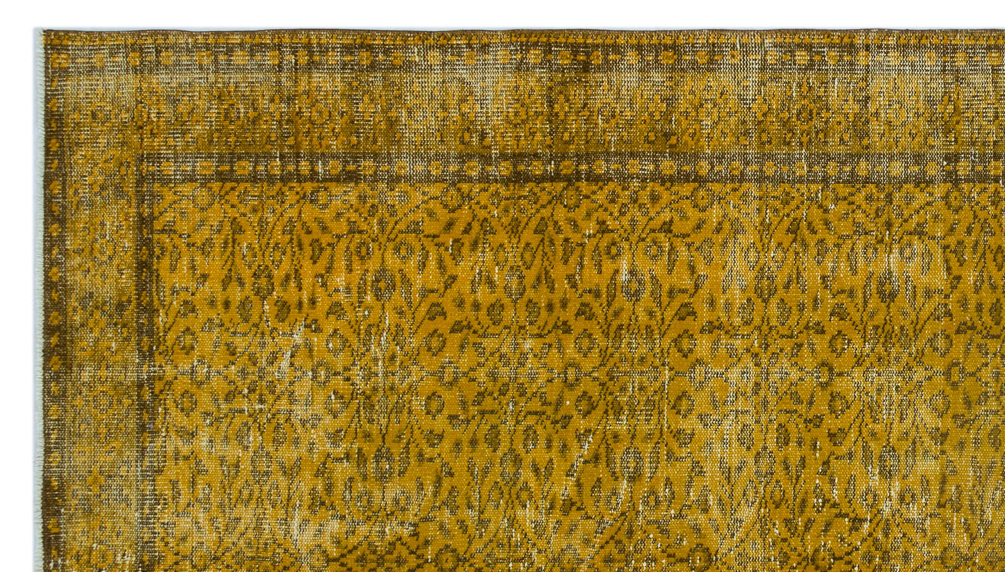 Mustard yellow and brown distressed rug with a traditional floral pattern and a bordered edge.