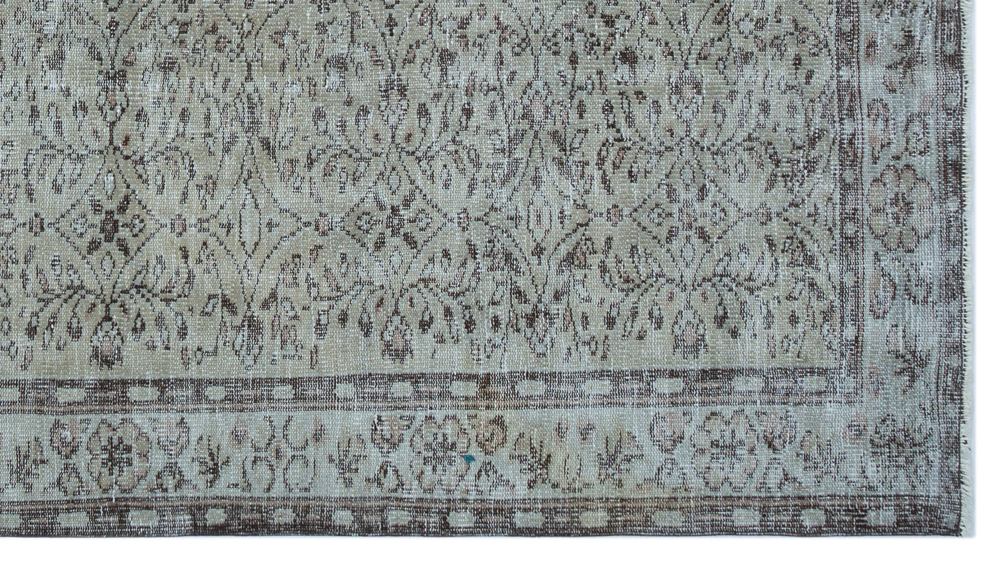 Beige and brown distressed vintage-style rug with a traditional floral medallion pattern and a geometric border.