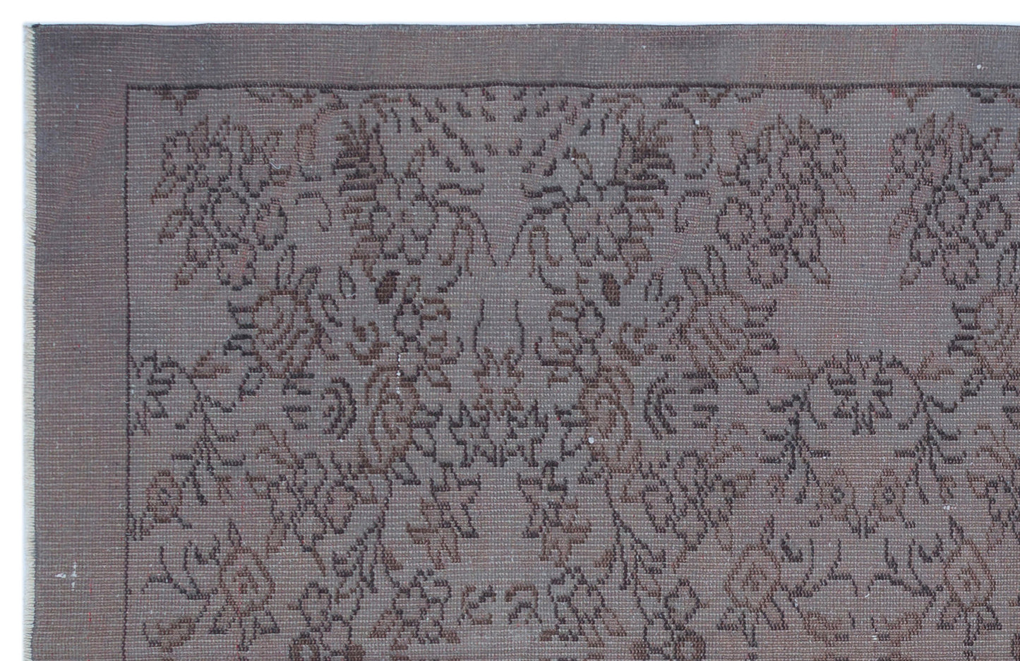 Dark brown monochromatic rug with a distressed, traditional floral medallion pattern and a simple border.