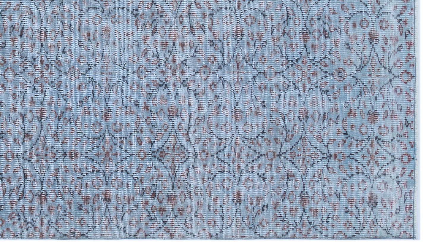 Light blue rug with a distressed floral medallion pattern in muted rust and charcoal grey.