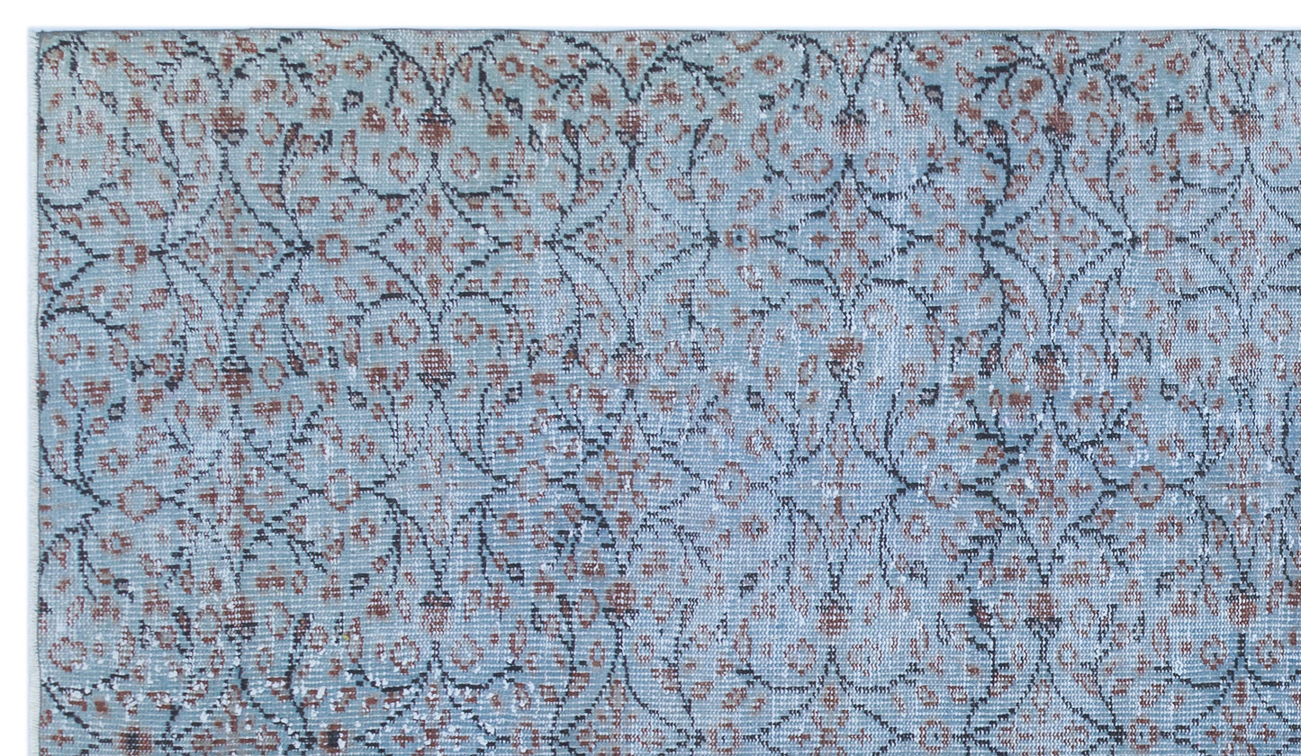 Light blue rug with a distressed floral medallion pattern in rust and charcoal grey.