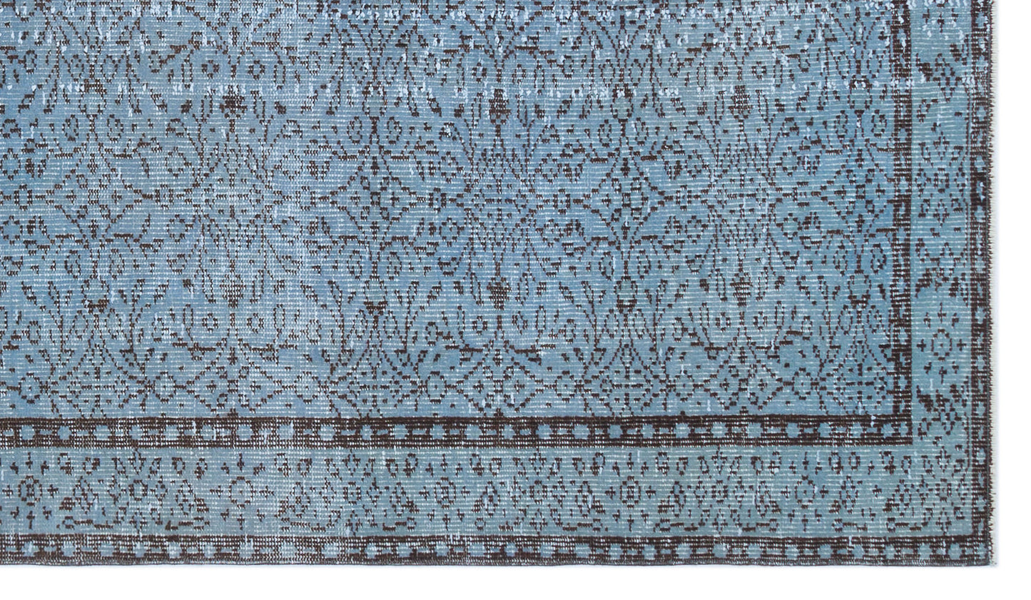 Light blue and dark brown distressed rug with a traditional floral medallion pattern and a geometric border.