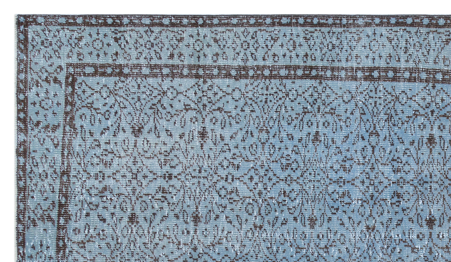 Light blue and dark brown traditional rug with a distressed floral medallion pattern and a geometric border.
