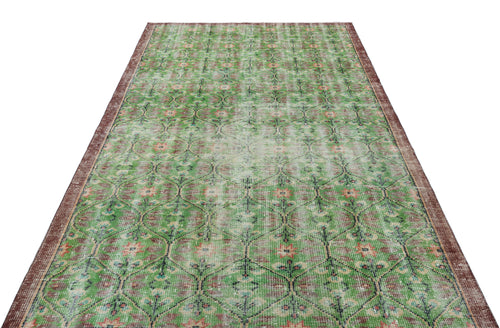 Load image 1 in gallery view. Distressed green and brown vintage-style rug with a repeating geometric floral pattern and a dark border.