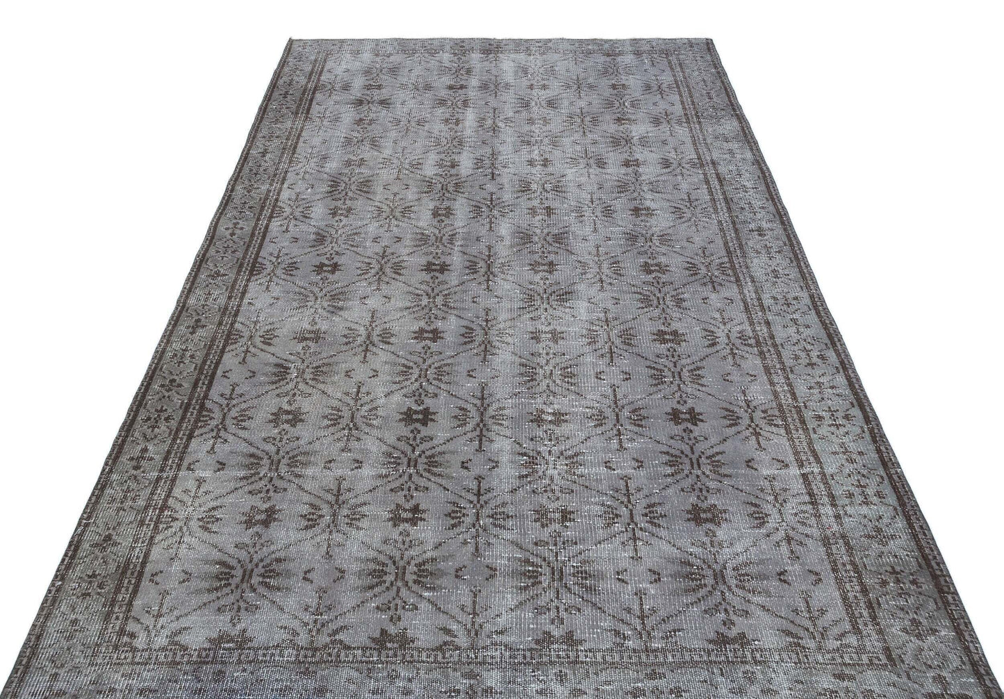 Grey and brown distressed rug with a repeating geometric floral lattice pattern and a wide decorative border.