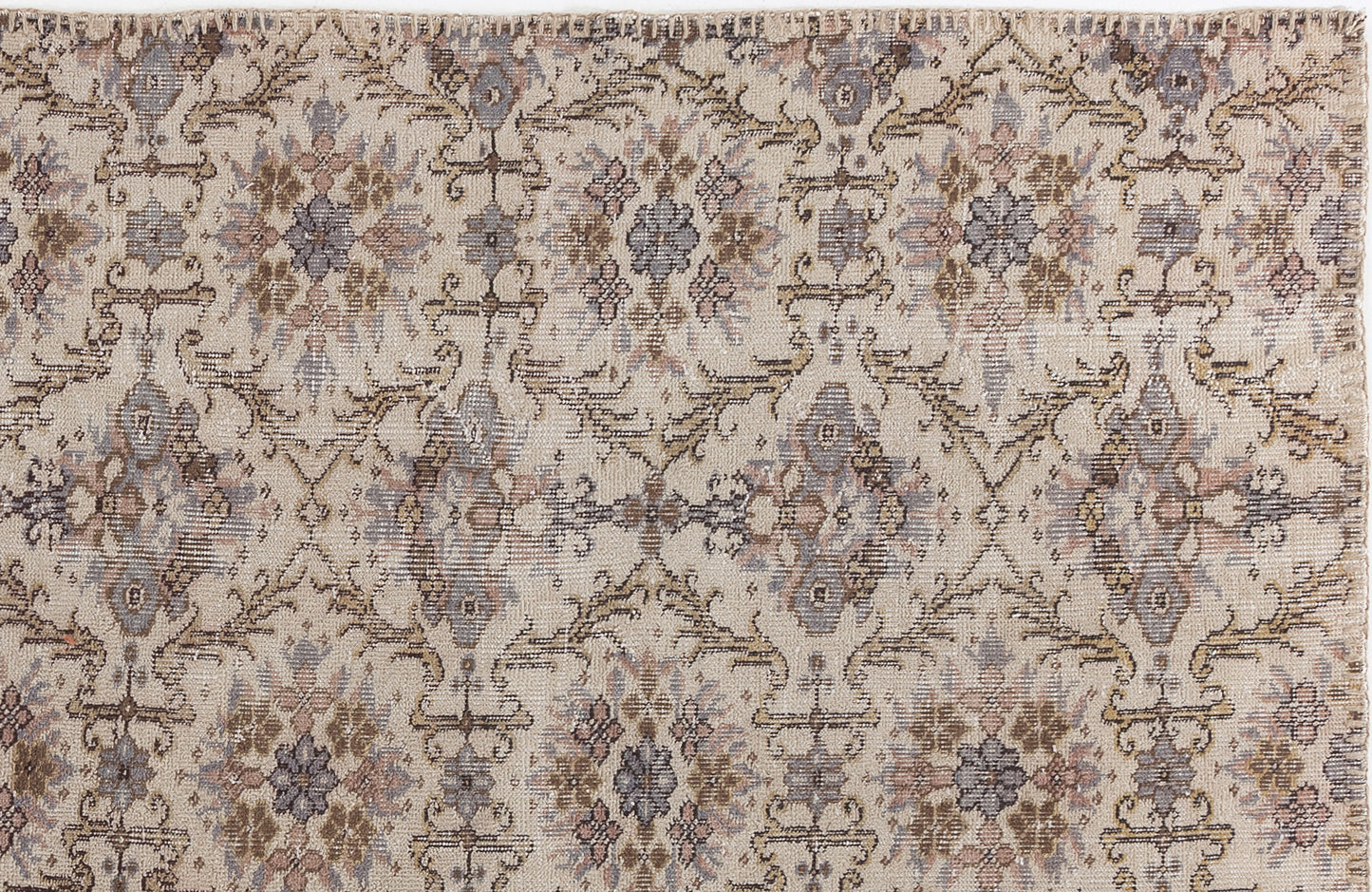 Beige rug with a distressed, repeating floral medallion pattern in muted brown, grey, and dusty rose tones.