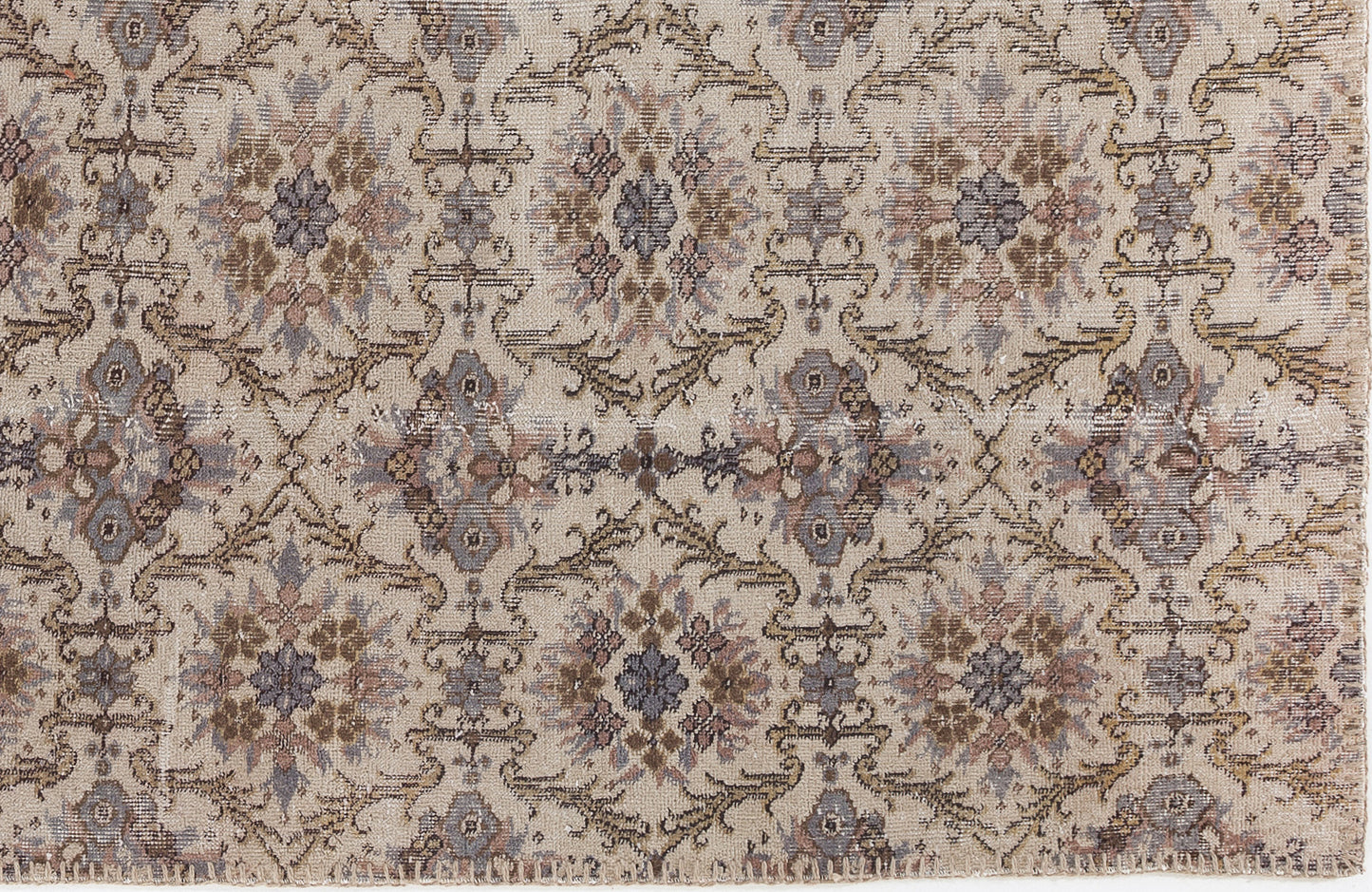 Beige rug with a distressed, repeating floral medallion pattern in muted tones of brown, grey, and mauve.