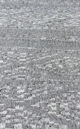 Close-up of Modern Mist - Washable Double-Sided Kilims - AR01: a textured gray woven fabric with a subtle geometric pattern, featuring varied surfaces of small raised and flat areas for a modern look.