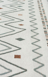 Close-up of Sand Horizon - Washable Double-Sided Kilims (AR05) on a white background, showing green and brown geometric patterns—zigzags, diamonds, and small squares arranged in rows.