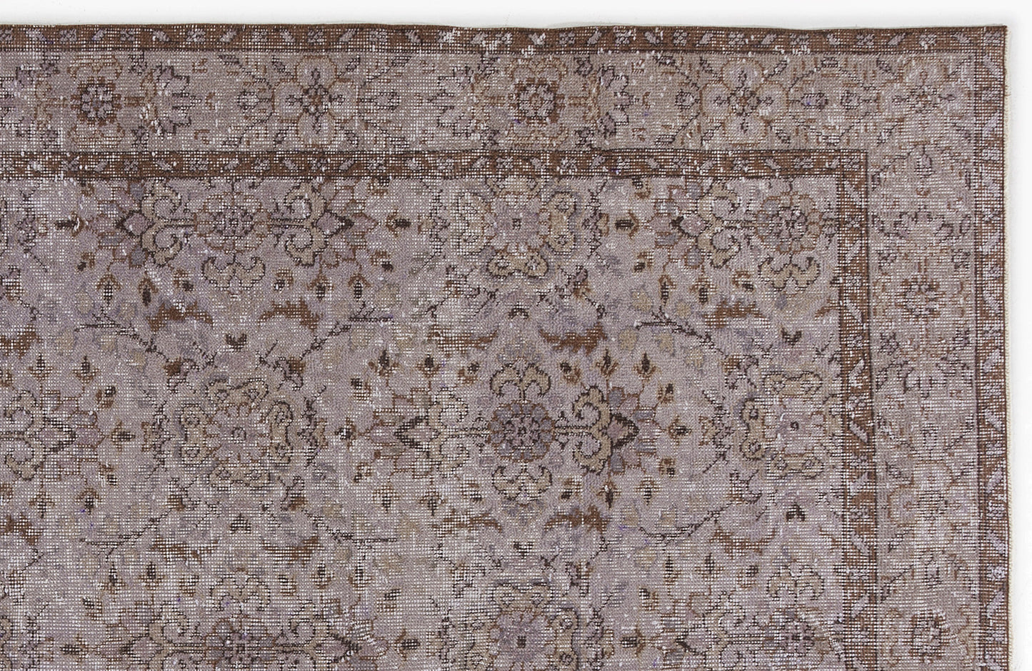 Distressed taupe and brown rug with a traditional floral medallion pattern and a detailed geometric border.
