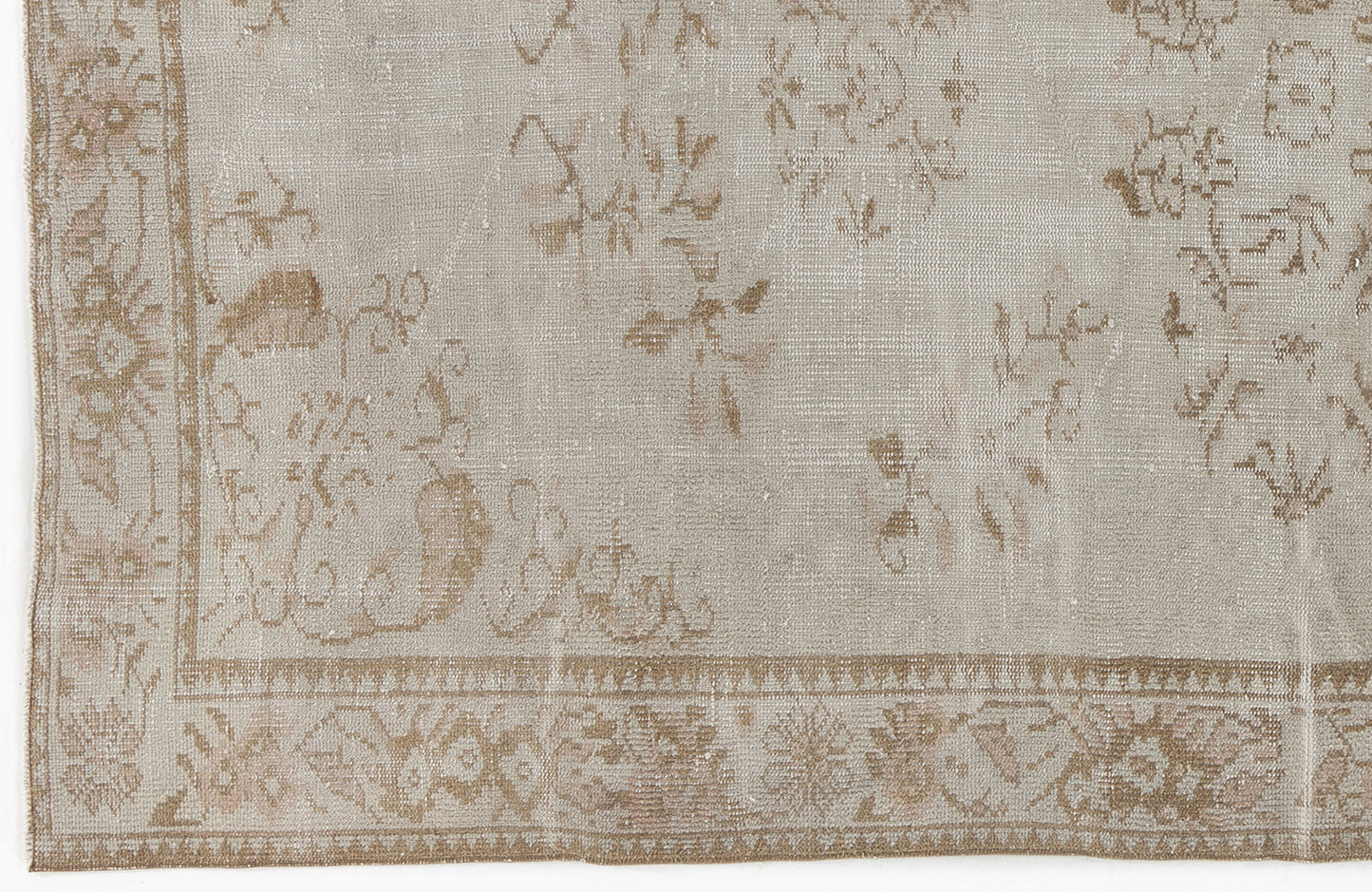 Beige and taupe distressed rug with a faded traditional floral pattern and a decorative border.